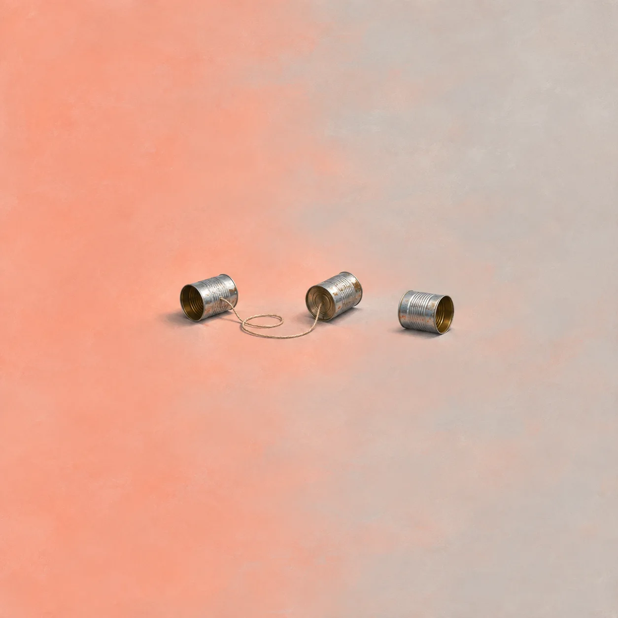 Three tin cans lie on a coral and grey surface, with loose string between two of them.