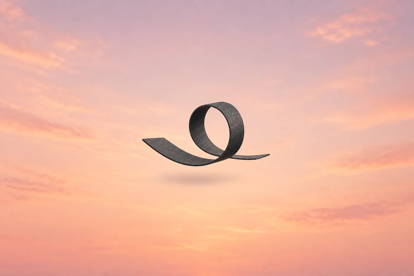 A ribbon of dark asphalt curls into an open loop in a pink sky.