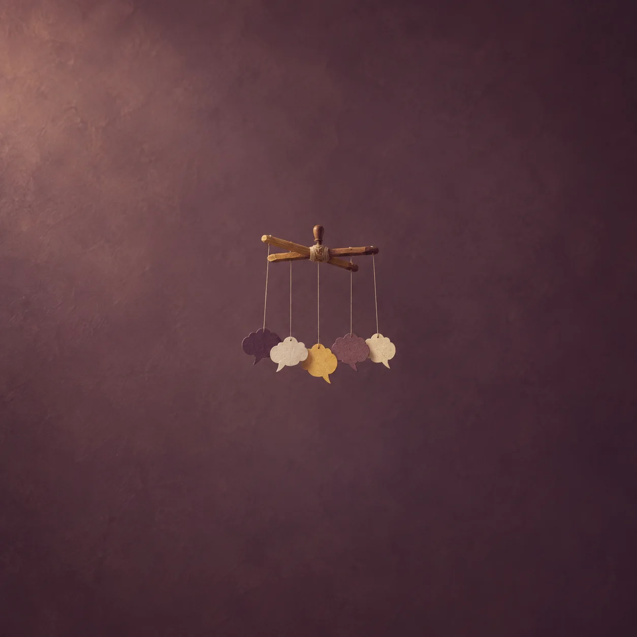 Blank paper speech bubbles hang by fine threads from crossed wooden bars against a muted plum background.