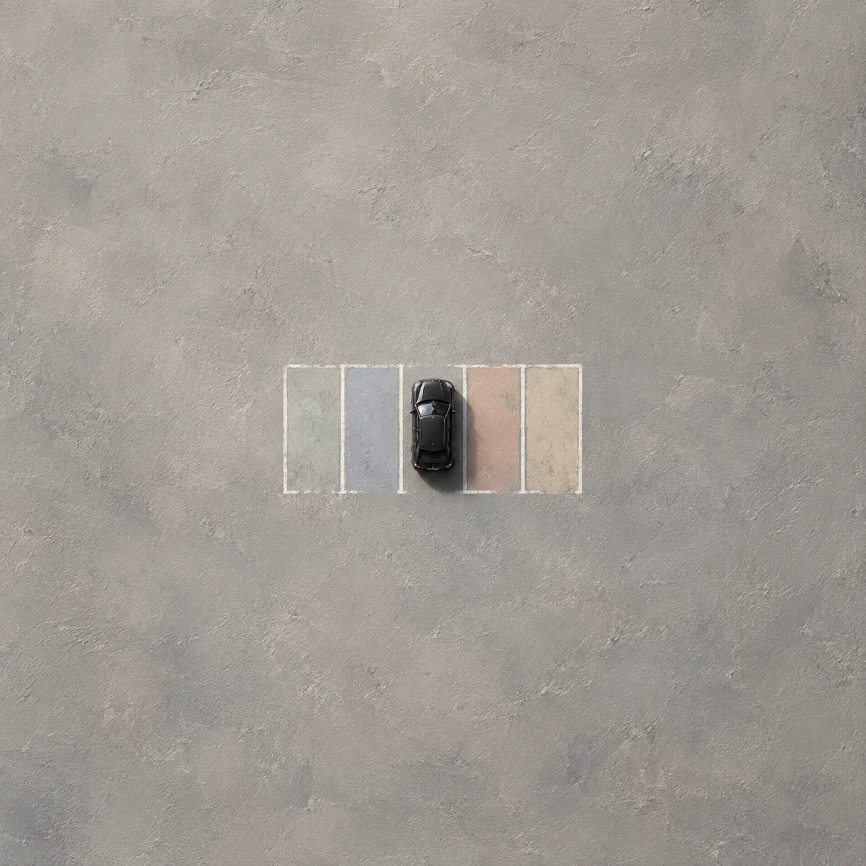 A black toy car sits in a row of empty pastel-colored parking spaces viewed from above on gray ground.