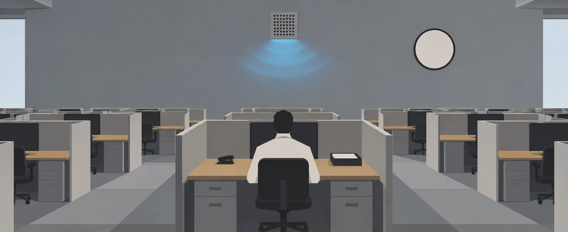 A lone office worker in a white shirt sits at his desk in a vast, empty grey cubicle floor.