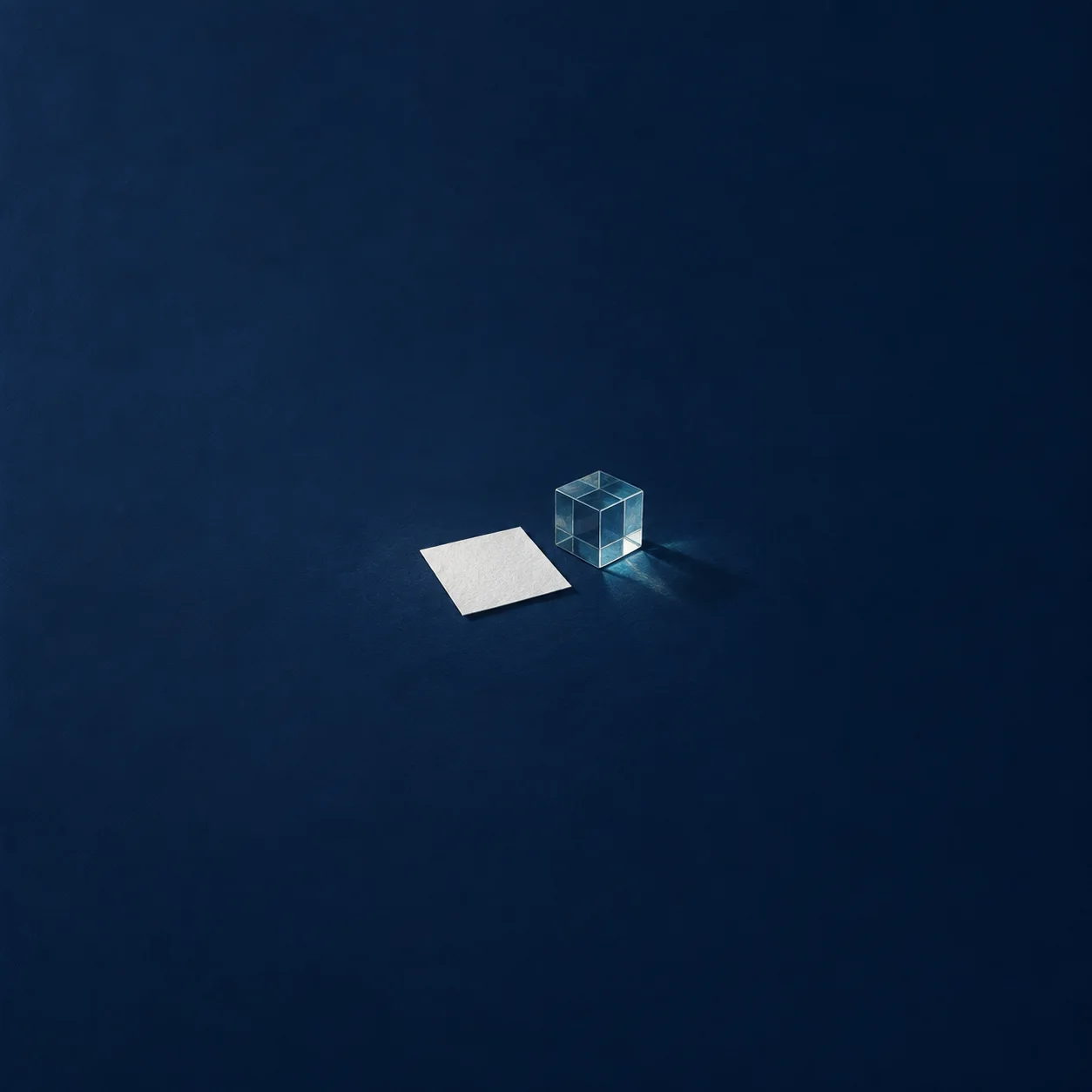A flat white paper square beside a transparent blue glass cube and its shadow against a navy background.