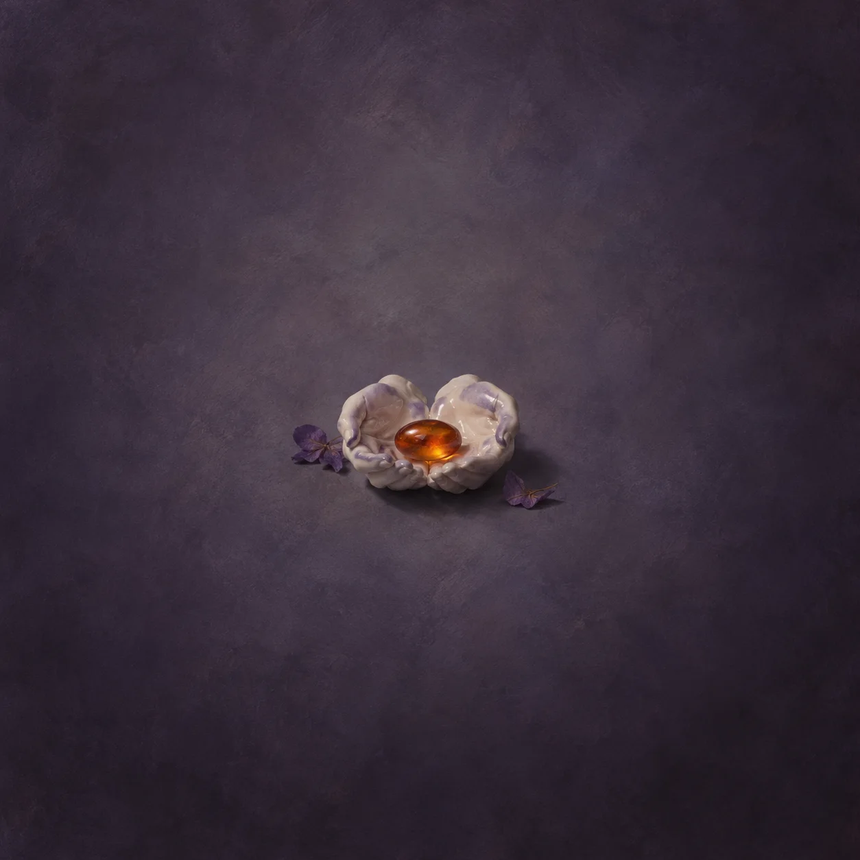 Ivory ceramic cupped hands cradling an amber glass ember-bead, with violet petals beside