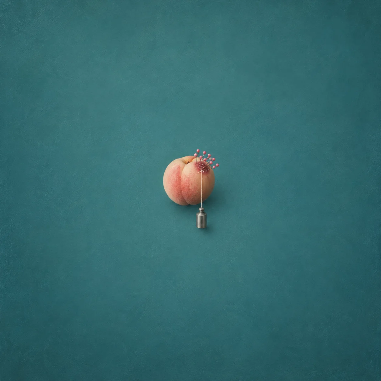 A peach with pink-headed pins and a small silver weight hanging beneath it against a teal background.
