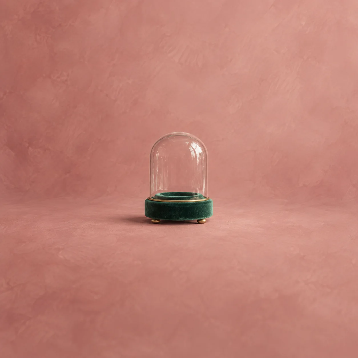 An empty glass dome on an emerald-green pedestal against a dusty-rose background.