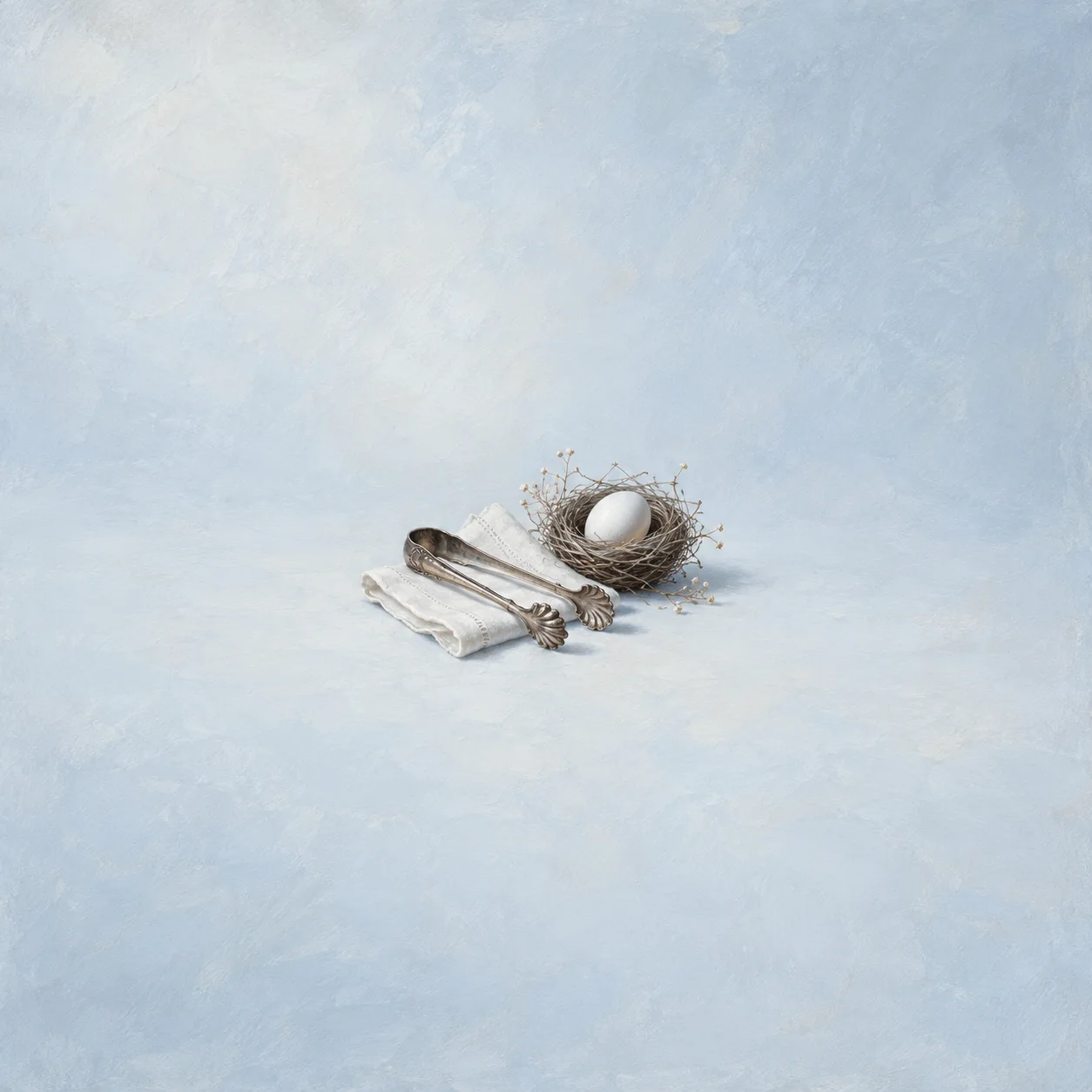 Metal ice tongs rest on folded white cloth beside a single egg in a small twig nest on pale blue ground.