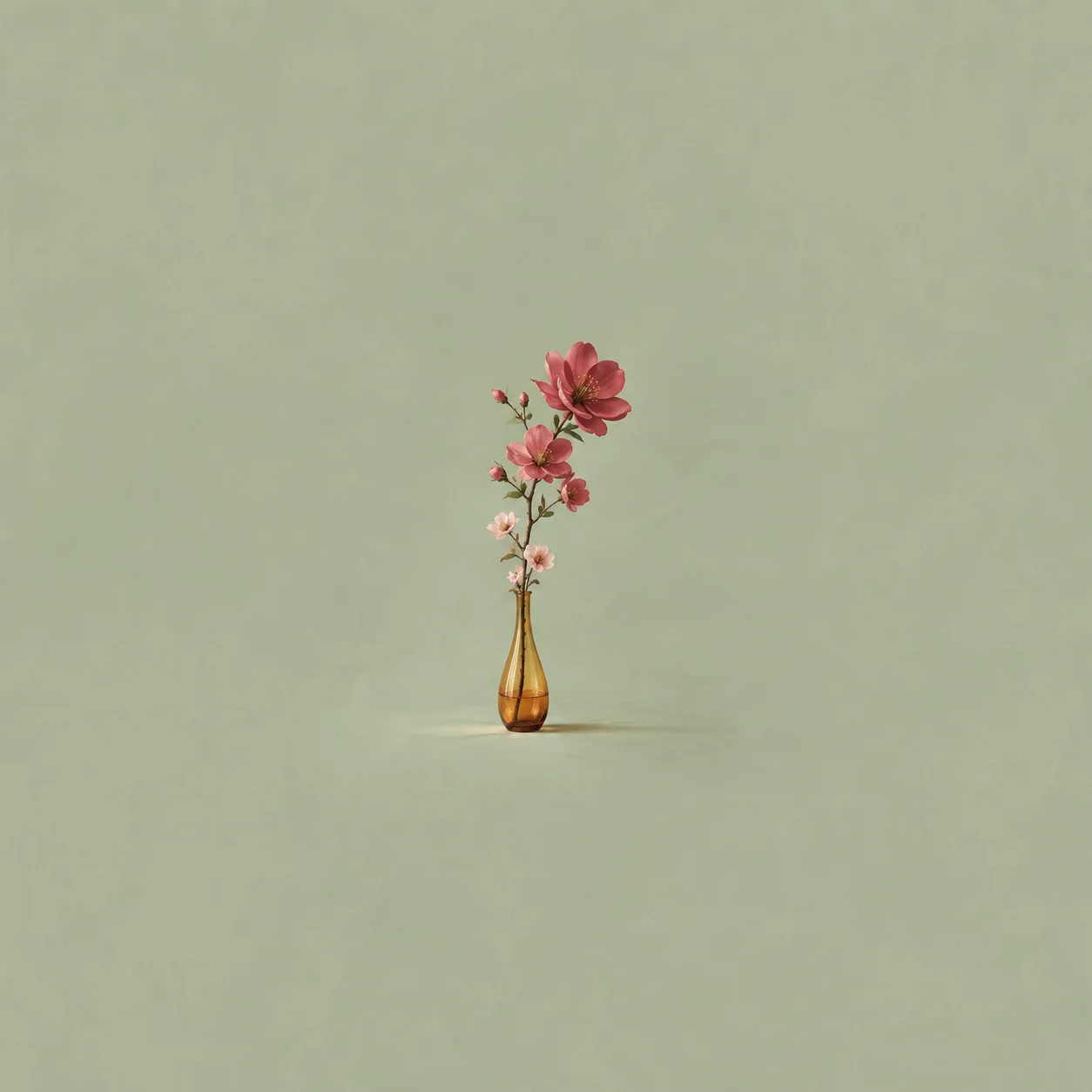 An amber glass vase holding a flowering branch with larger, deeper pink blooms towards the top on a pale green background.