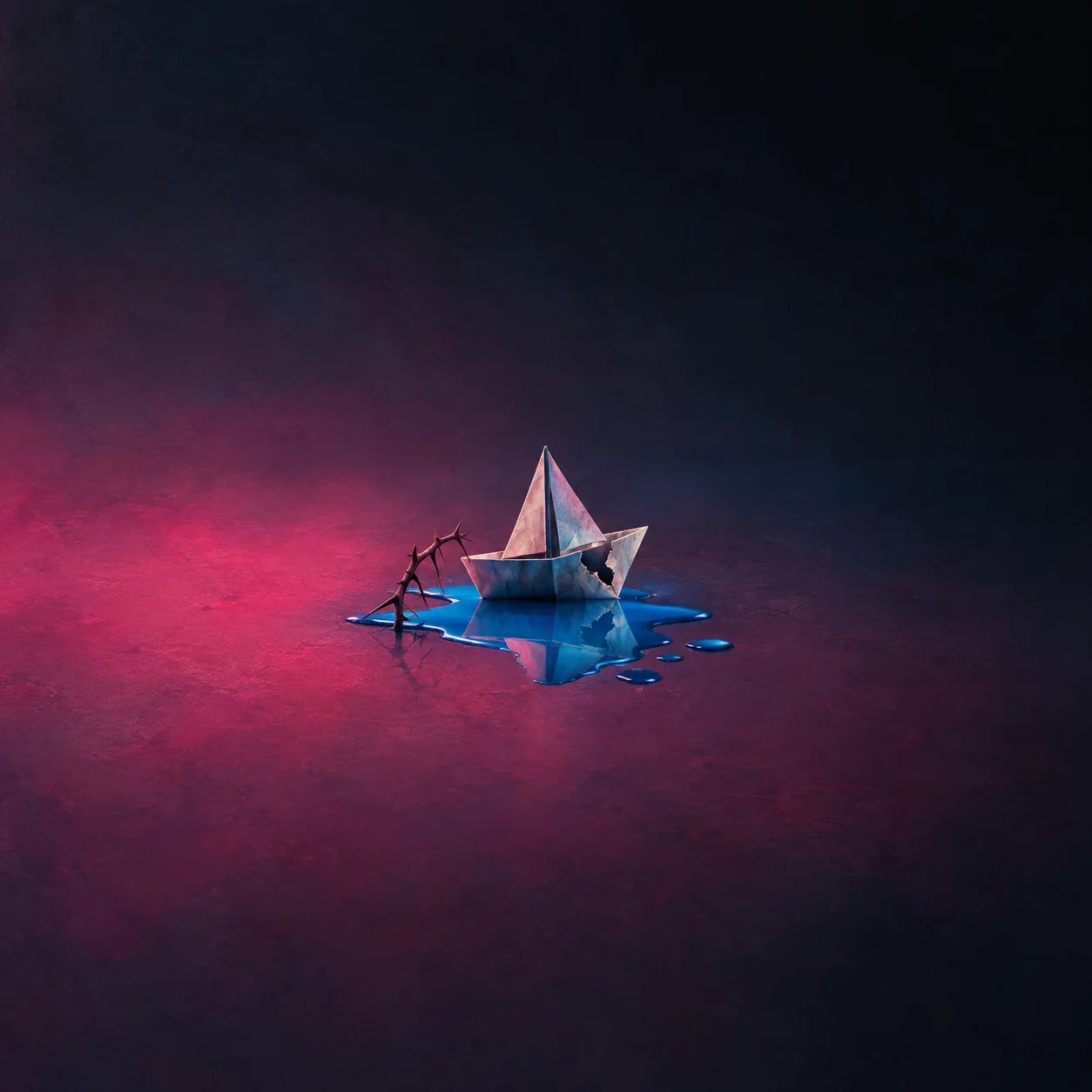 A small paper sailboat rests in a bright-blue puddle beside a thorny twig.