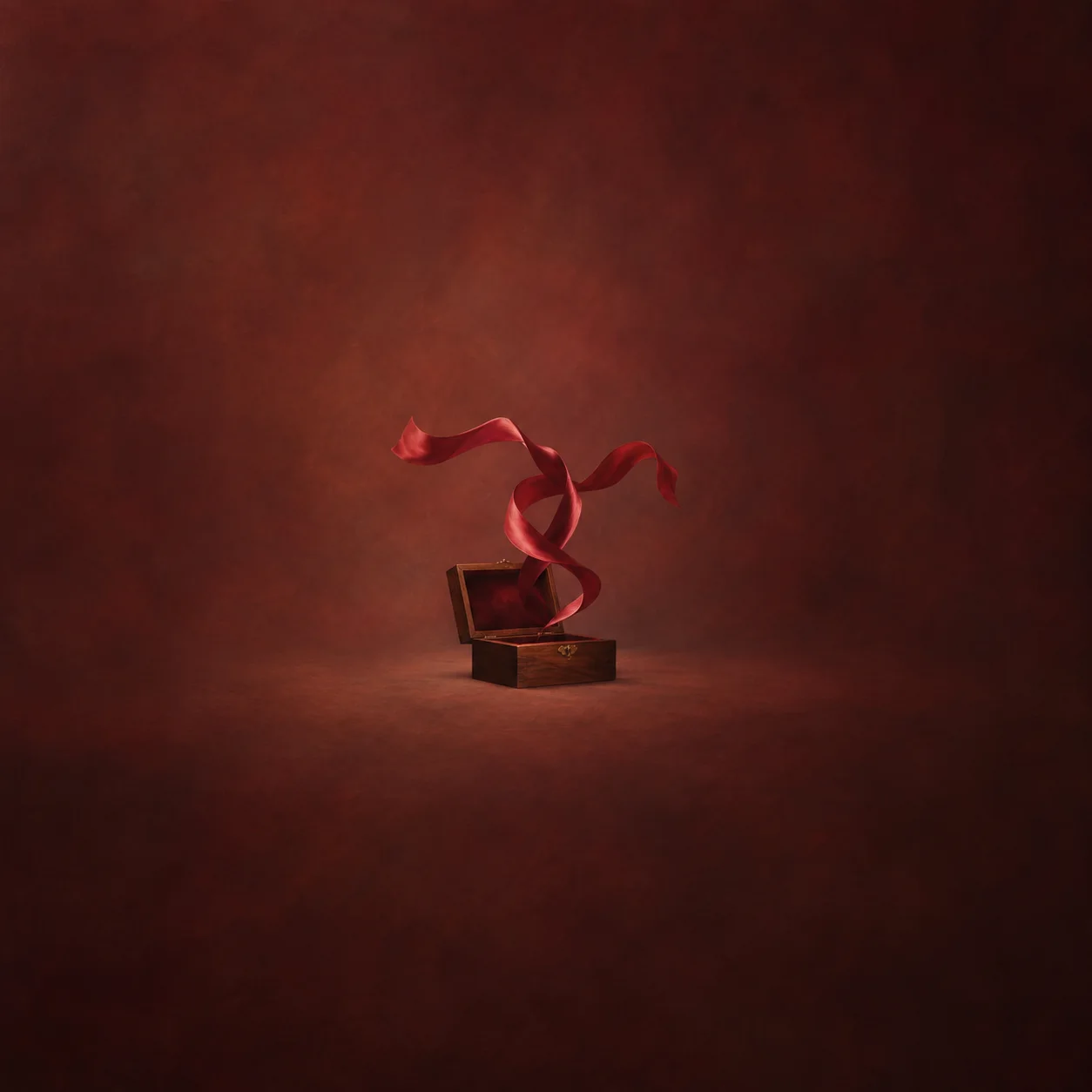 Painterly curling red ribbons floating above an open wooden box against deep red.