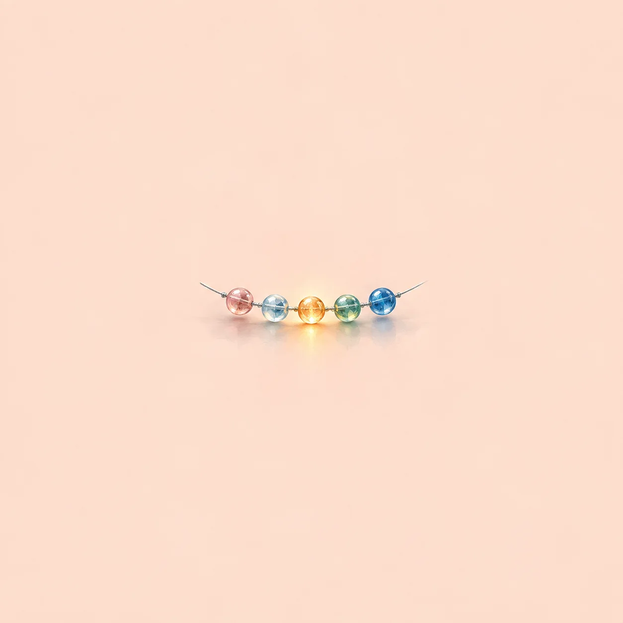 Five small coloured glass beads on a silver thread, one glowing.