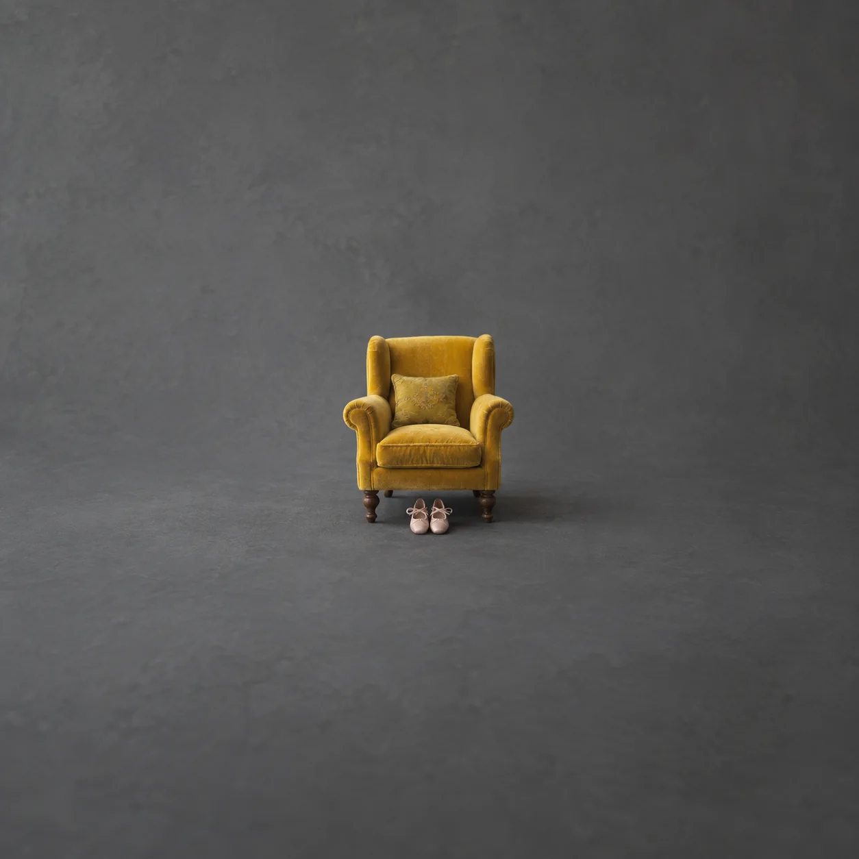 A small mustard-yellow velvet armchair with a pair of dancing shoes tucked beneath it on a grey background.
