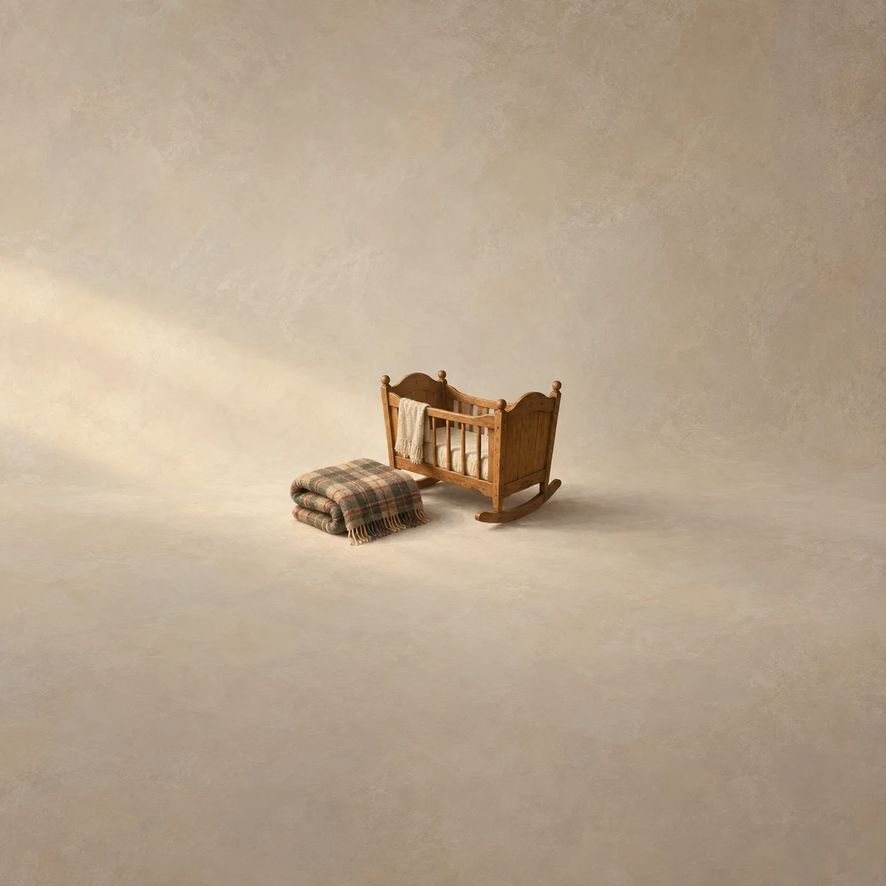A folded plaid blanket rests beside a small wooden cradle with pale cloth hanging over its side.