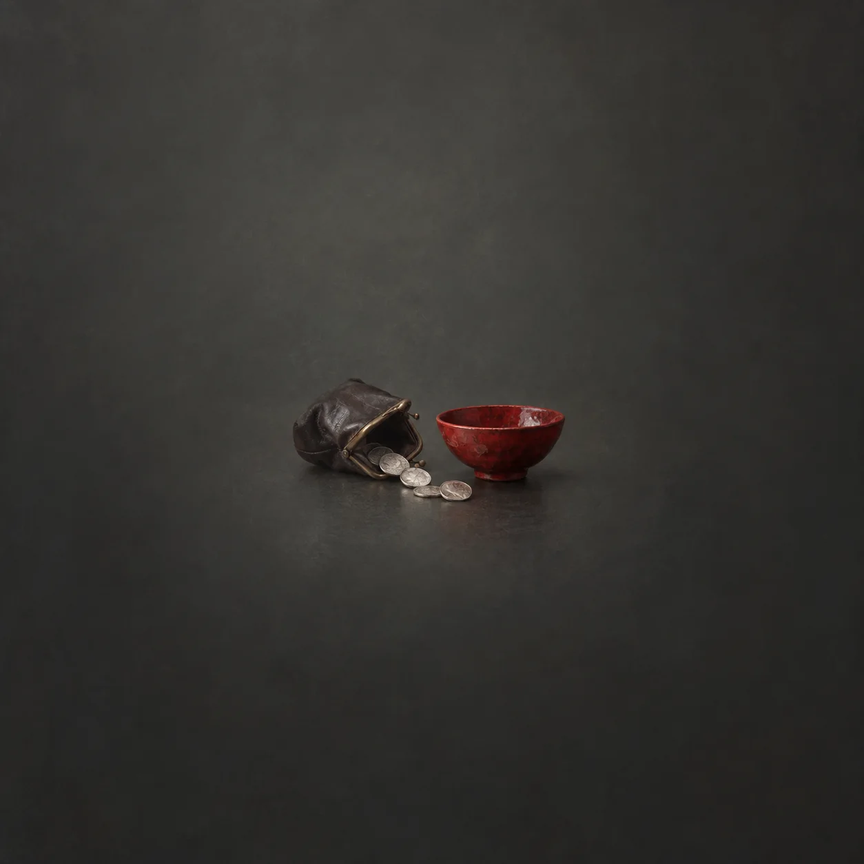 A dark leather purse spills silver coins toward a shallow red bowl.