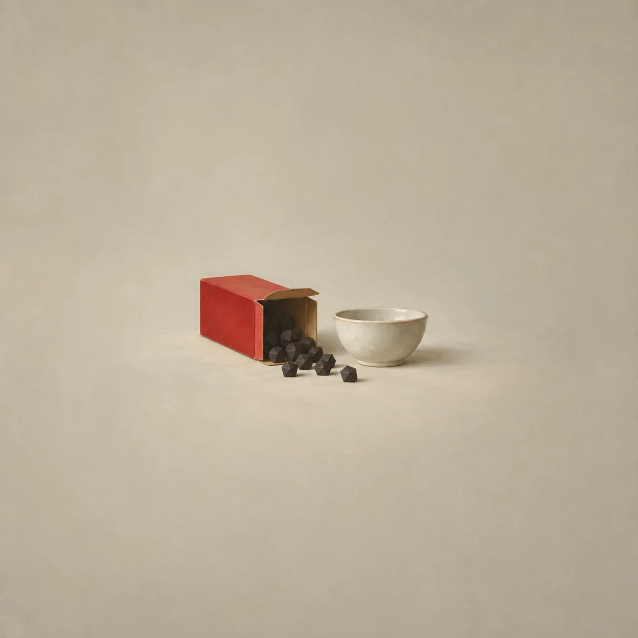 Dark geometric pieces spill from an open red box beside a pale bowl.
