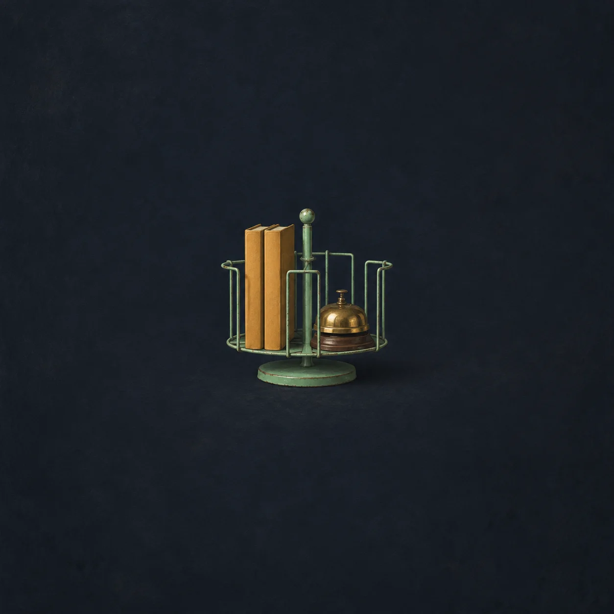 A mint-green wire book rack holding two plain ochre books and a small brass bell against a dark blue background.