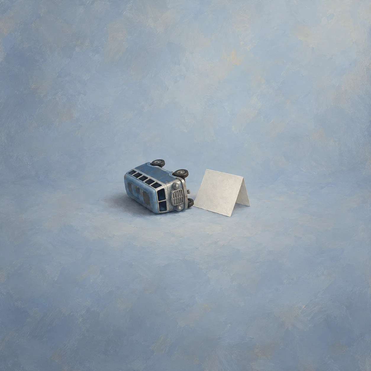 Unmarked blue toy bus tipped beside a blank folded sheet