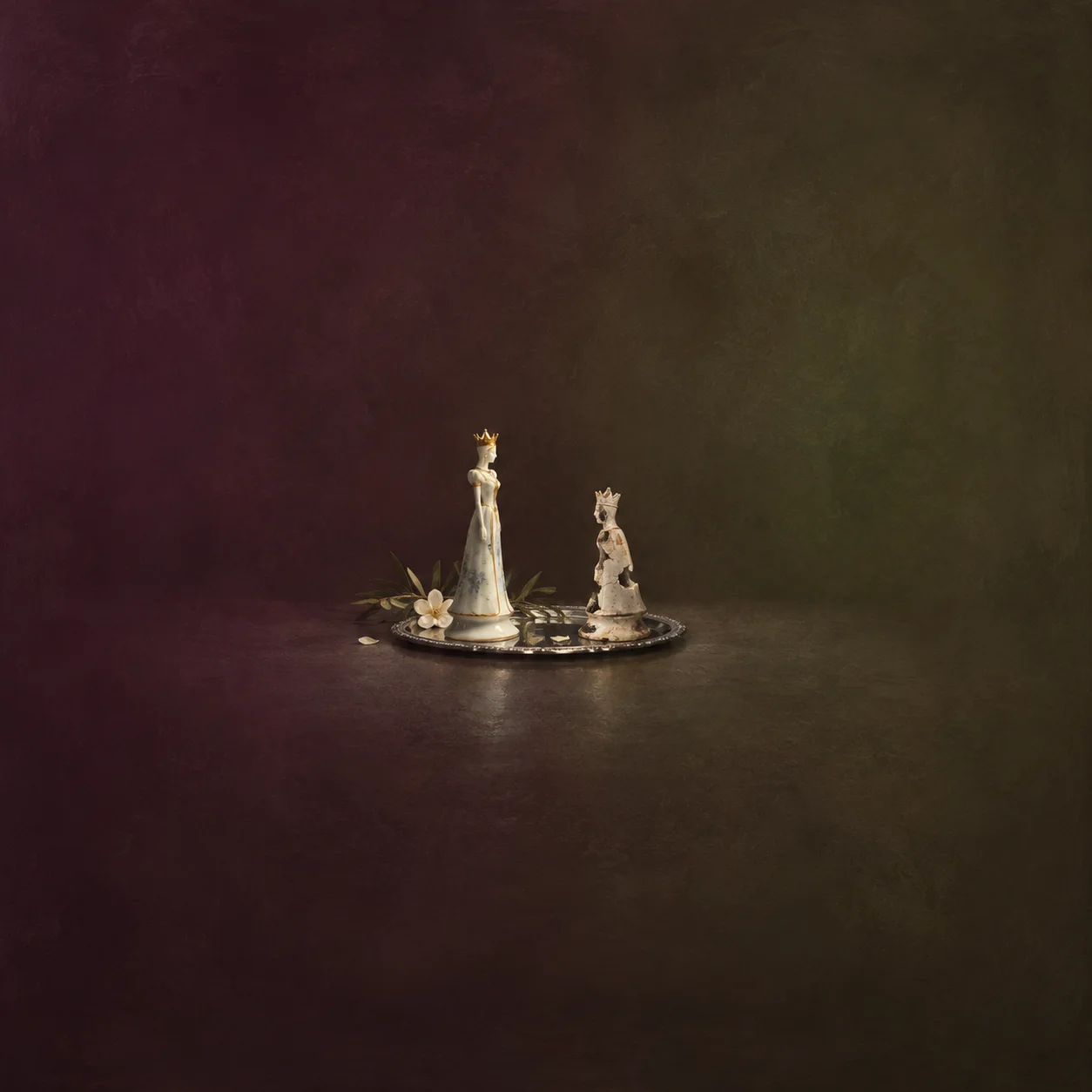 Two porcelain figurines, one polished and one chipped, facing each other on a small silver tray against a plum background.