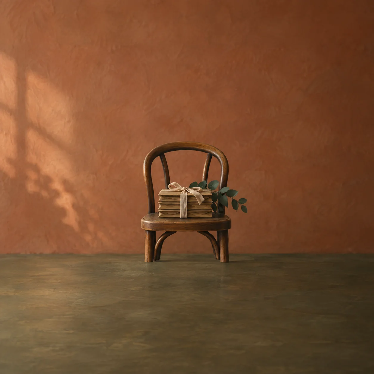 A bundle of brown envelopes tied with ribbon resting on the seat of a wooden chair beside green leaves.
