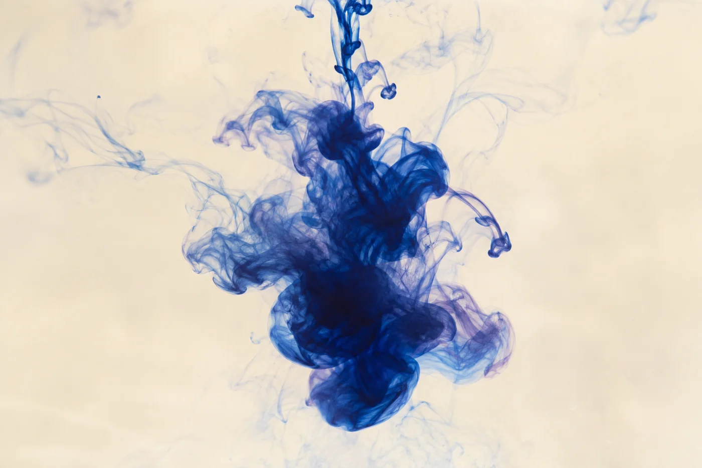 Deep blue ink curls and spreads through pale, clear water.