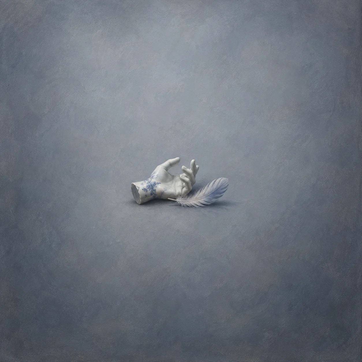 White porcelain hand with curled fingers beside a pale feather