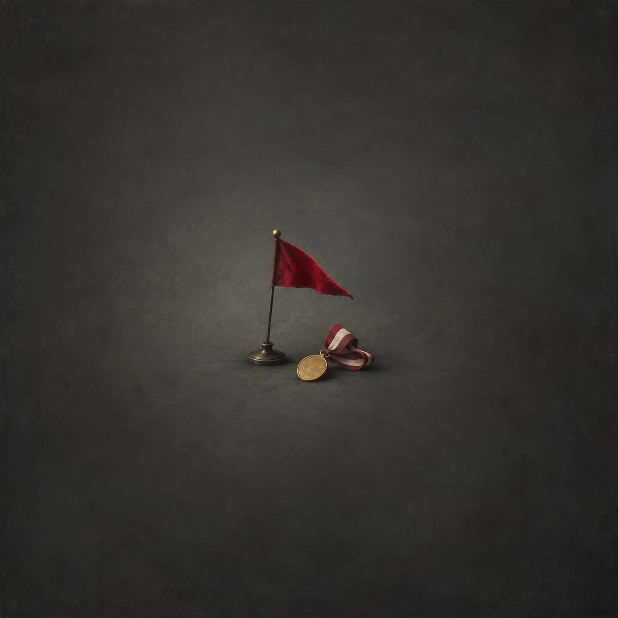 A small crimson flag on a pole beside a gold medal and ribbon against a charcoal background.