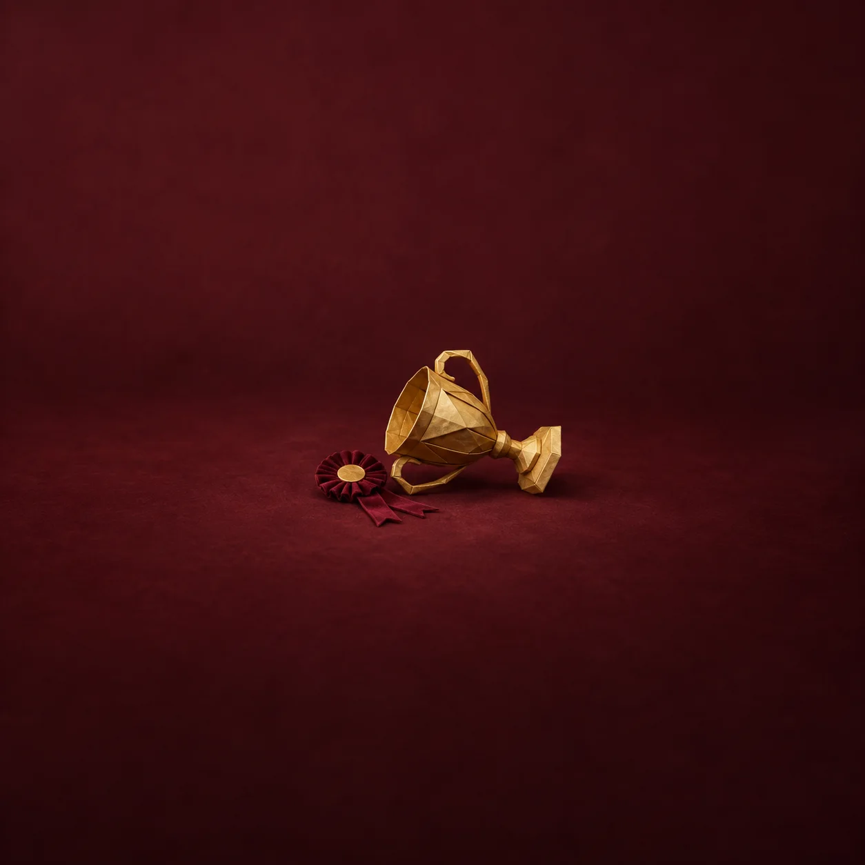A tipped-over golden trophy beside a small burgundy rosette on a dark red background.