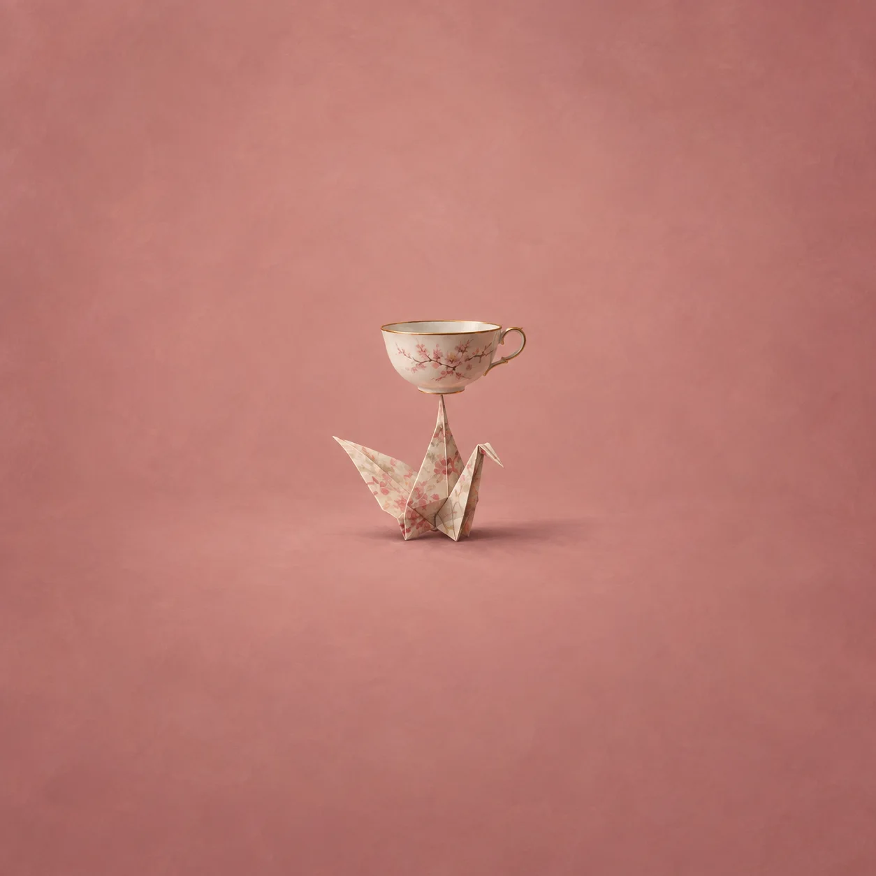 Painterly floral teacup balanced on a folded paper crane against dusty pink.