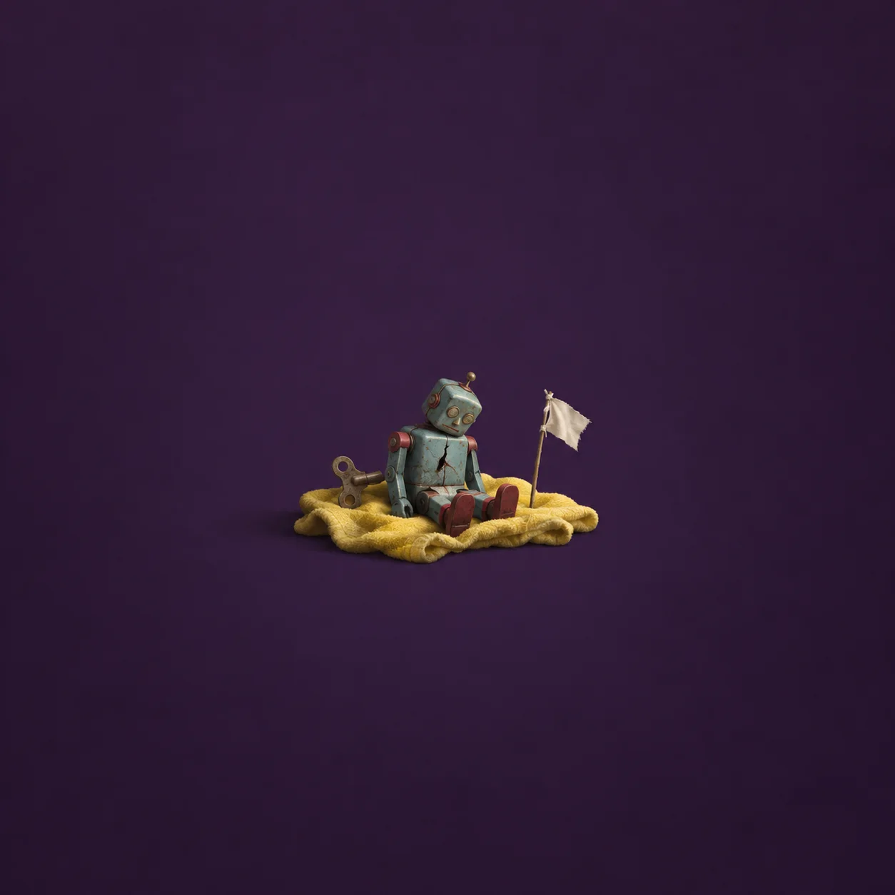 A slumped tin wind-up robot sits on yellow cloth beside a loose key and a small white flag.