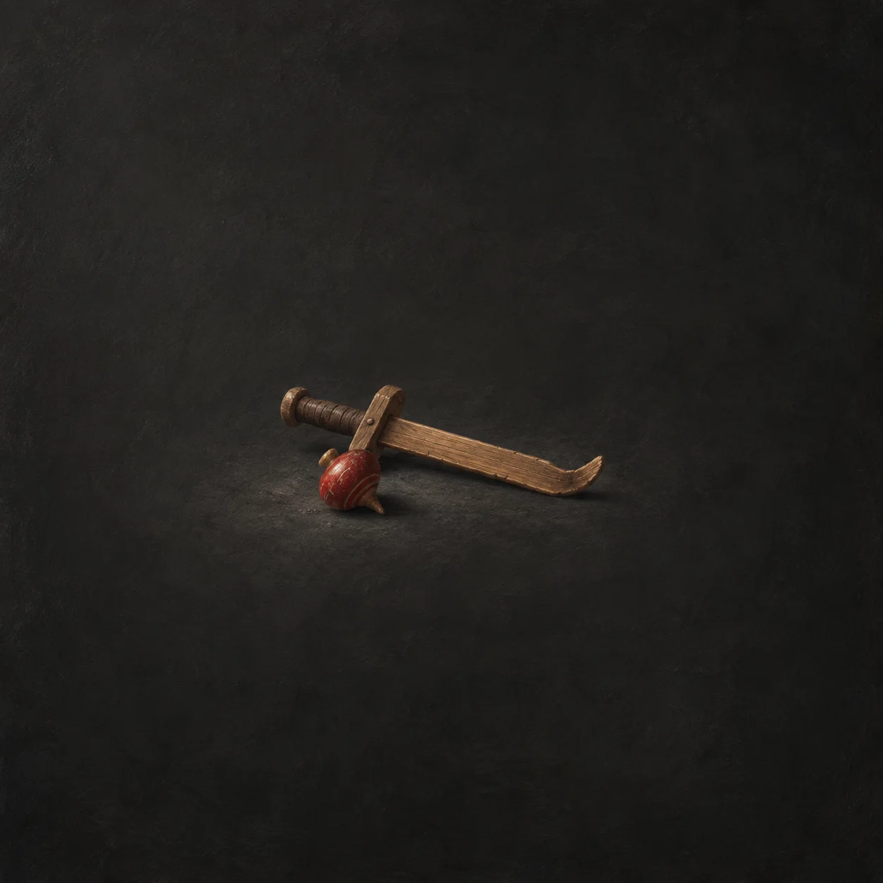 A bent wooden practice sword beside a red spinning top on a dark surface.