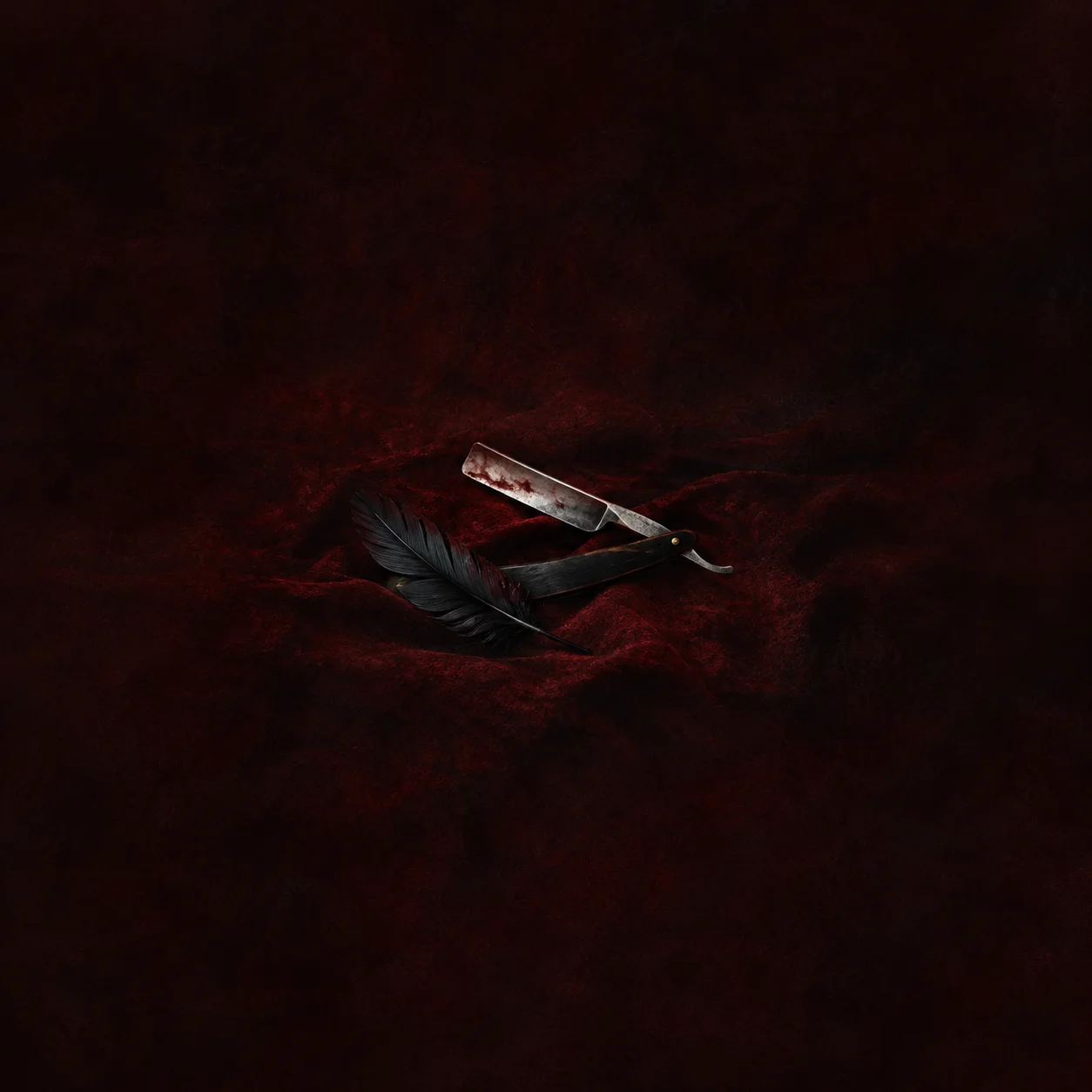 Painterly open straight razor beside a black feather on dark red fabric.