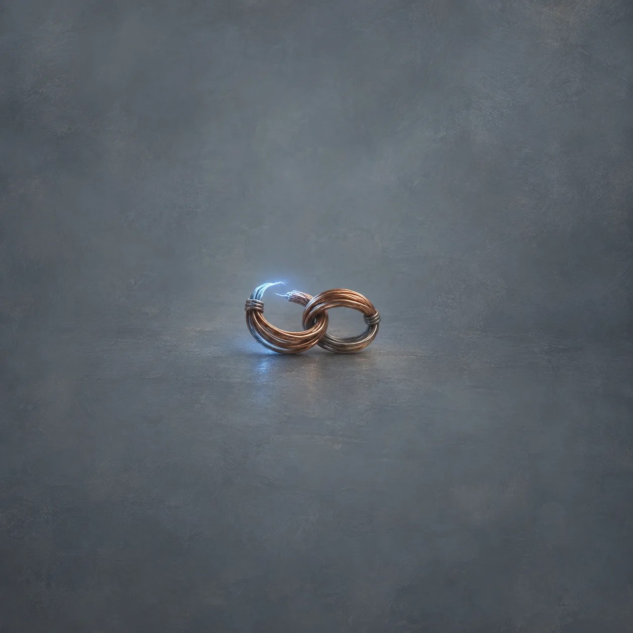 Two linked coils of copper wire rest on a blue-grey surface with a small blue glow between their ends.