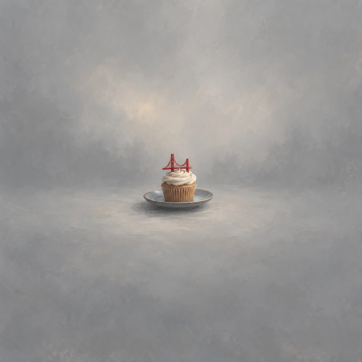 A cupcake on a grey saucer is topped with a tiny red bridge-shaped decoration.