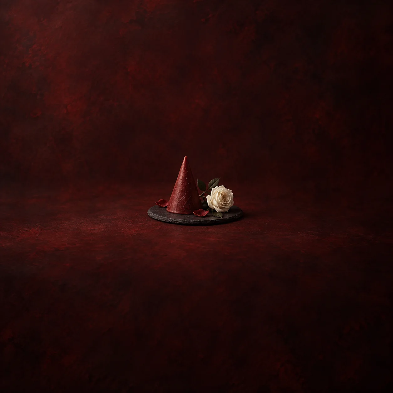 A red cone beside a white rose on a charcoal tray.