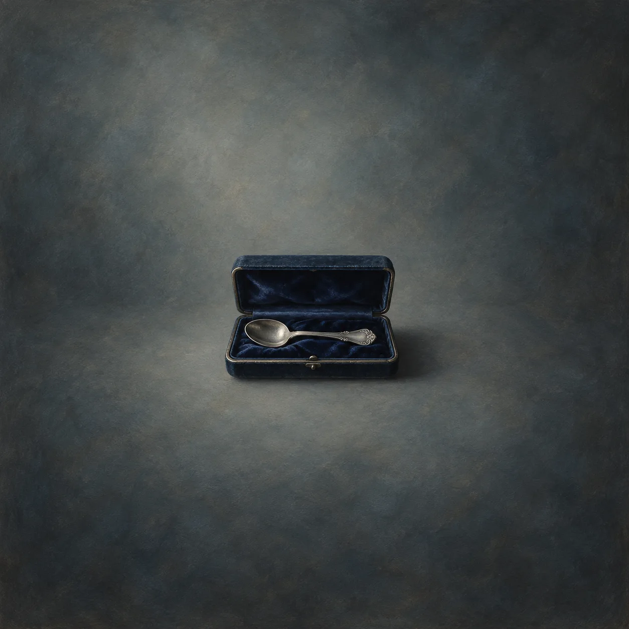 open navy velvet jewelry box with silver spoon centered in generous slate negative space
