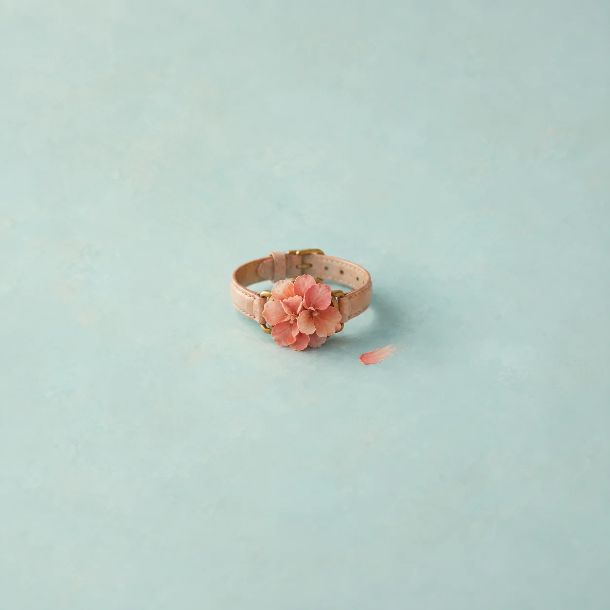 An empty wristwatch strap holding a cushion of coral petals where the face would be, on an aqua surface.