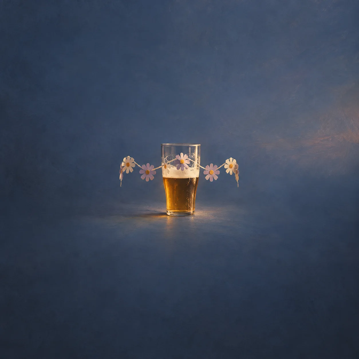 A half-full glass of beer is surrounded by small pale paper flowers.
