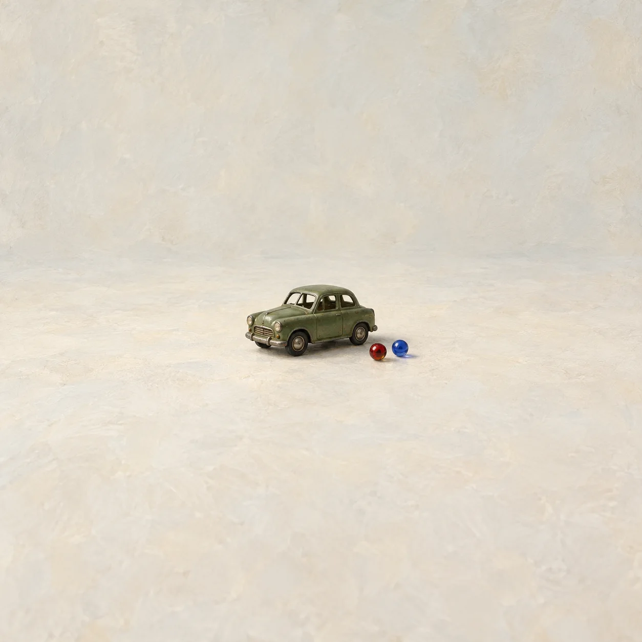 A small green toy car sits beside one red bead and one blue bead.