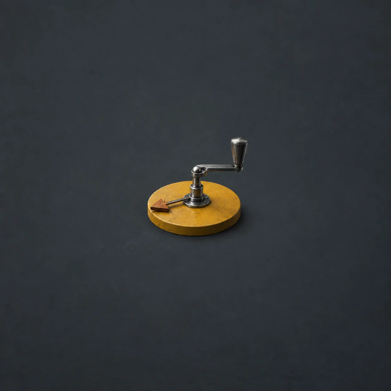 A polished steel crank mechanism spins a small wooden arrow on a mustard-yellow disc against a slate background.