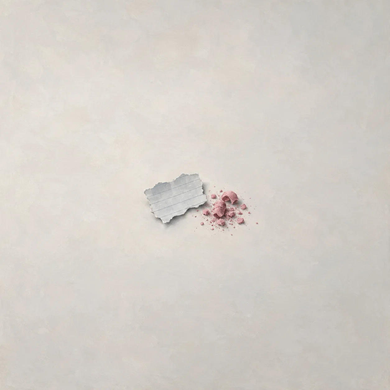 Painterly torn paper scrap beside pink eraser crumbs on a pale surface.