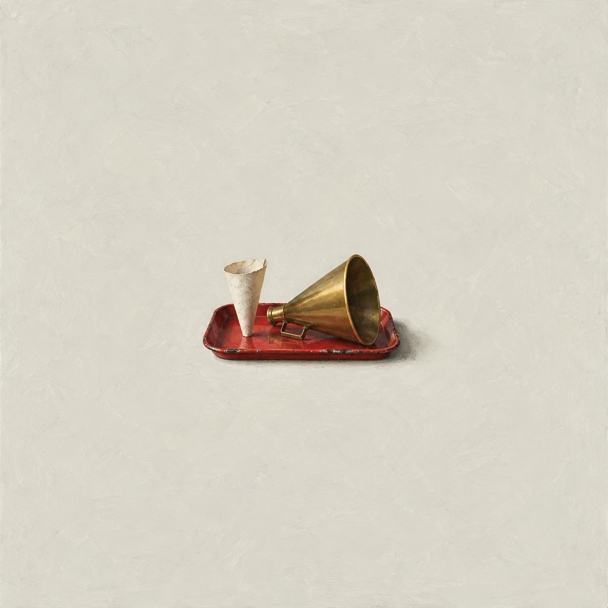 A brass horn and a pale paper cone rest on a red tray.