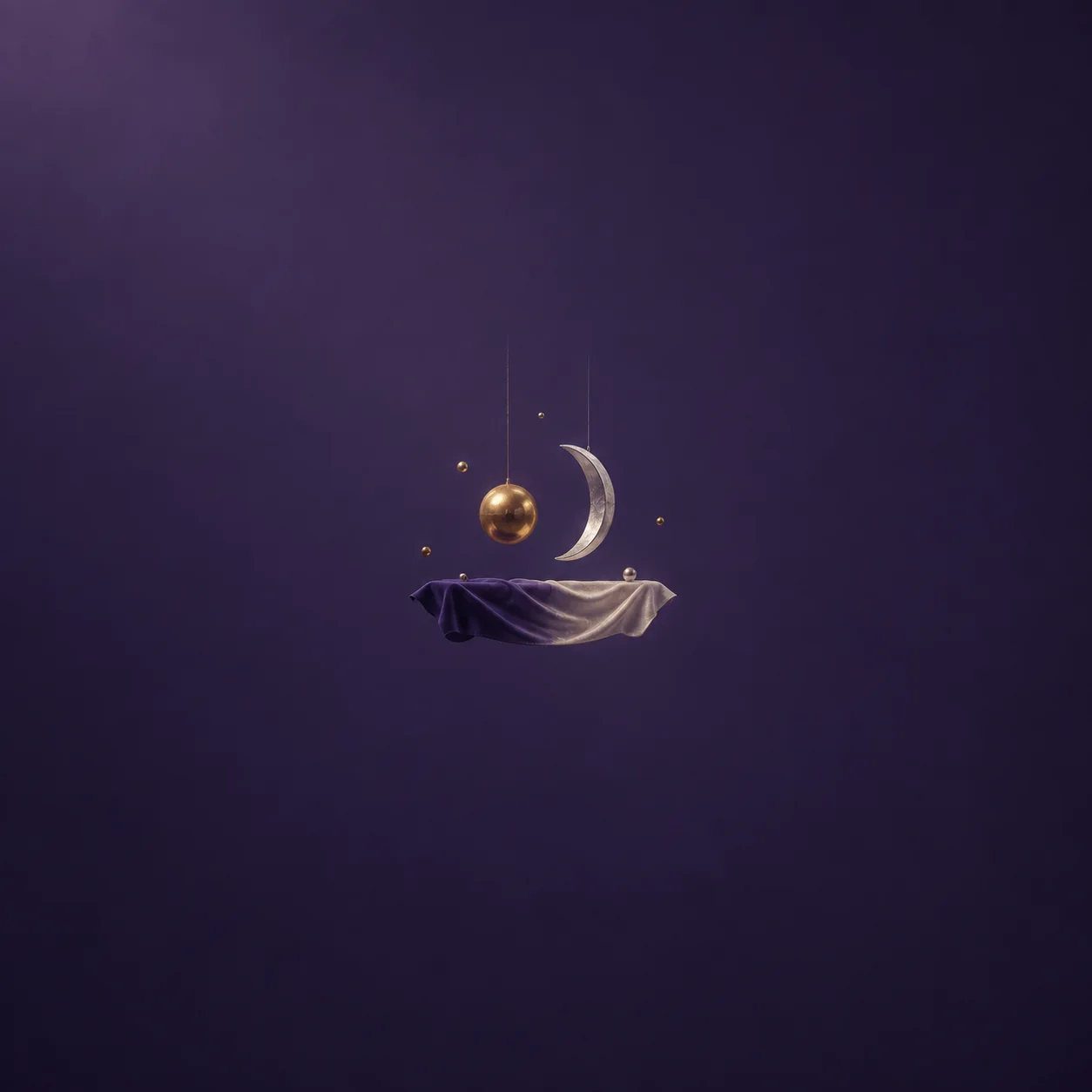 A brass sphere and silver crescent hanging on wires above cloth that fades from light to dark, with tiny beads.