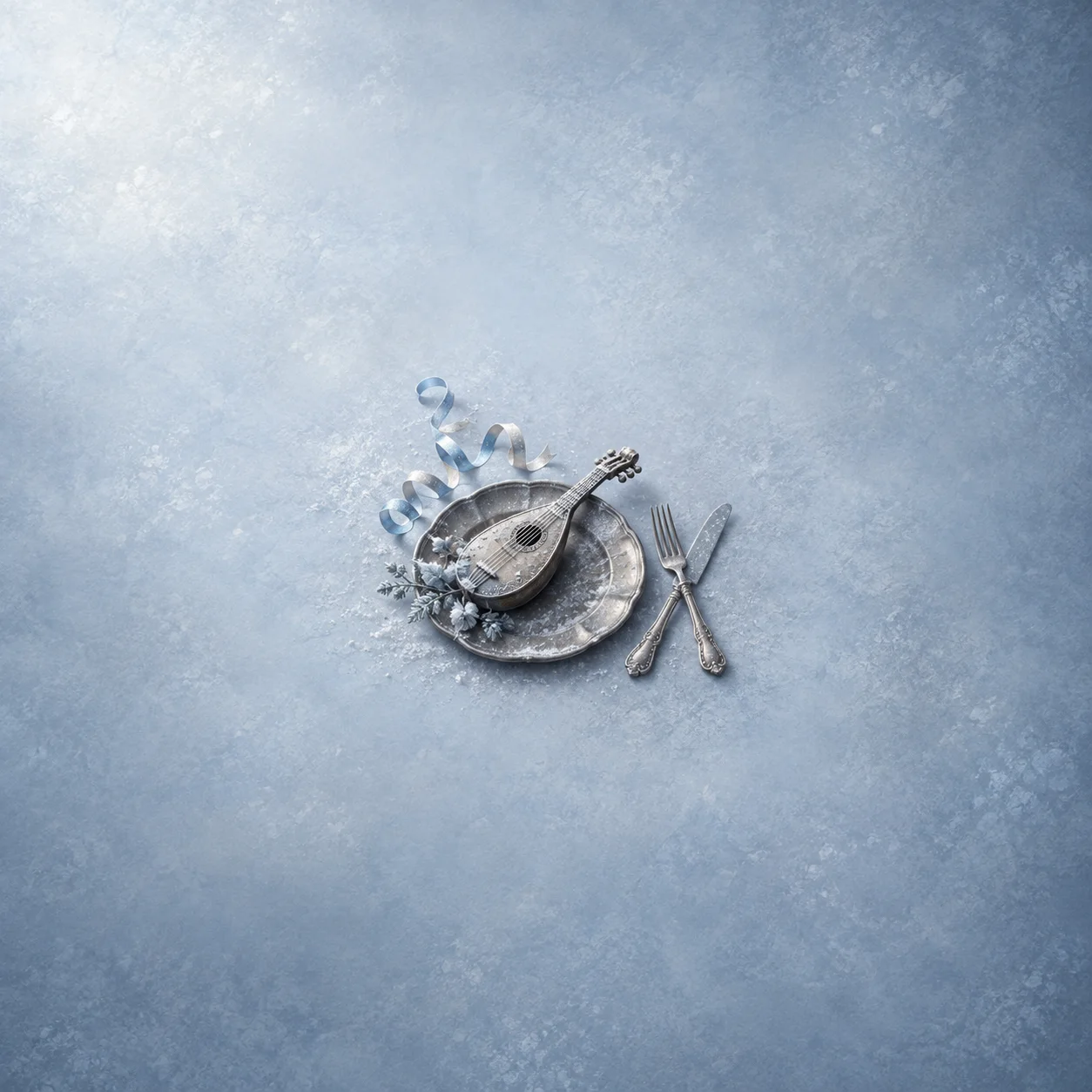 A snow-dusted miniature lute rests on a metal plate beside a knife, fork and curling paper streamers.