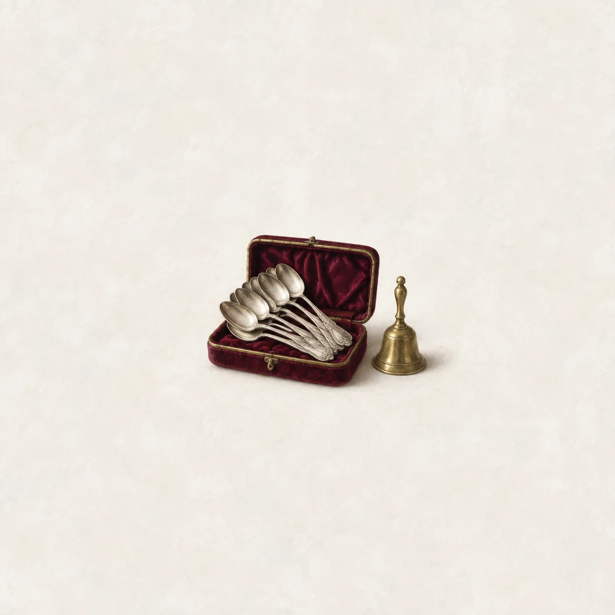 Silver-coloured spoons fill an open burgundy-lined case, with a small brass bell beside it.
