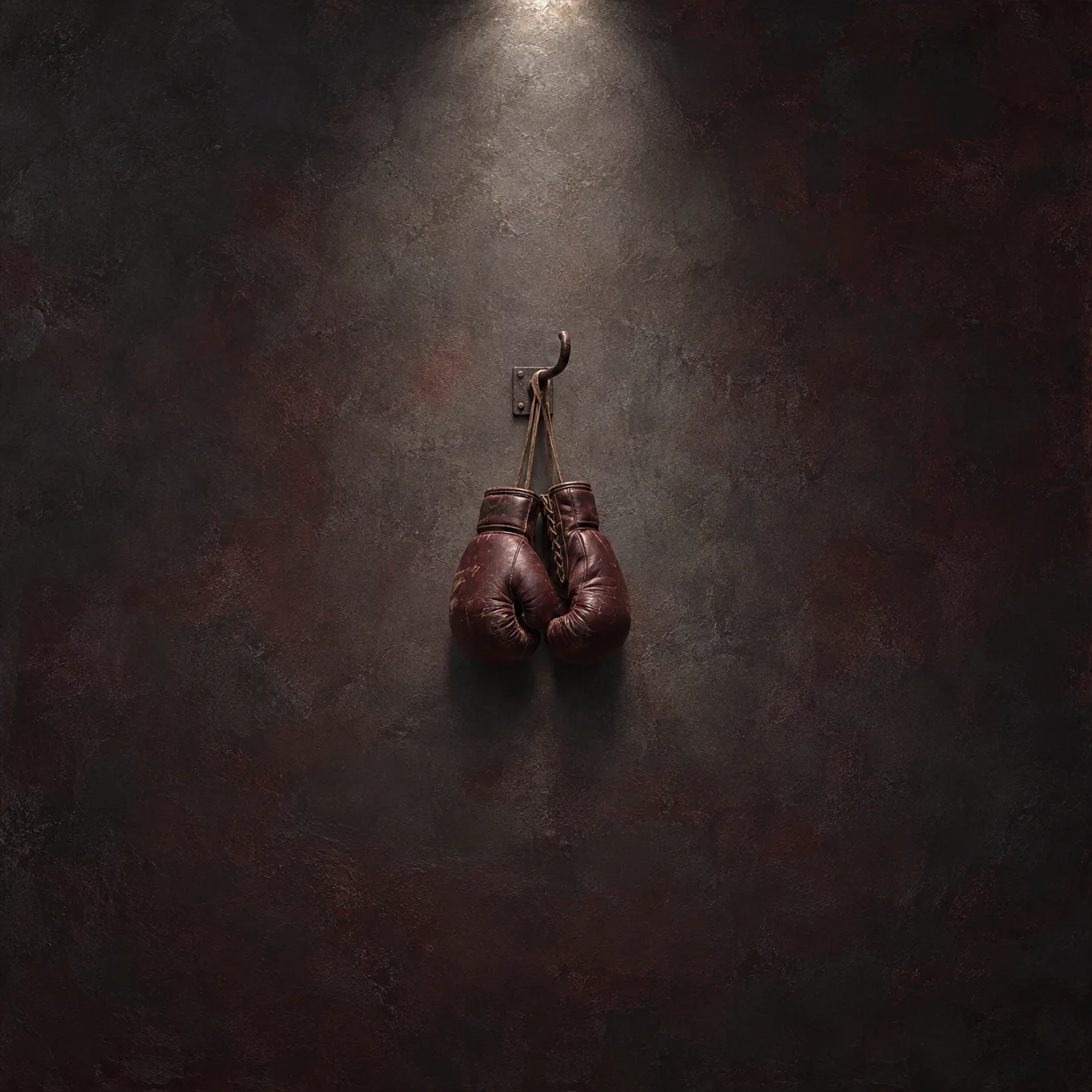 A pair of worn boxing gloves hangs by the laces from a hook against dark maroon.